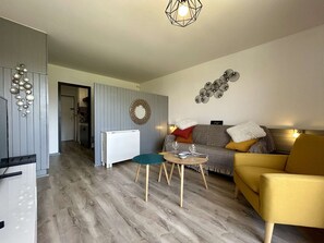 Ein modernes Wohnzimmer mit einer Couch, einem gelben Sessel, einem kleinen Tisch und einer Wanddekoration.