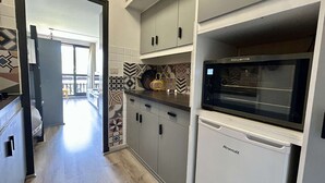 Una cocina moderna con microondas integrado, refrigerador y azulejos estampados en la pared de atrás.