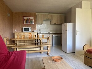 Eine kleine Küche mit Holzausstattung, einer Mikrowelle, einer Kaffeemaschine und einem Kühlschrank.