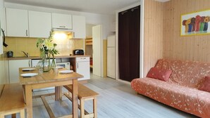 Ein gemütlicher, kompakter Wohnraum mit Küchenzeile, Esstisch und einer Couch.