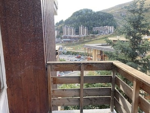 Holzgeländer eines Balkons mit Blick auf einen Parkplatz und Gebäude im Hintergrund.