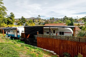 A caravan park with multiple caravans, a wooden fence, and a mountainous backdrop.