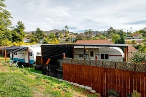 Un terrain de camping pour caravanes comprenant plusieurs caravanes, une clôture en bois et un paysage montagneux en arrière-plan.