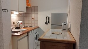Eine kompakte Küche mit Waschmaschine, Toaster und Wasserkocher.