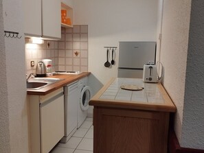 A compact kitchen with a washing machine, a toaster, and a kettle. - Charming T2 with WIFI, at the ski slopes - 6 guests (Orcières Merlette)