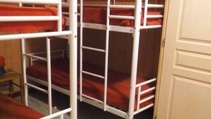 Ein Schlafzimmer mit Etagenbetten, weißen Metallgeländern und roter Bettwäsche.