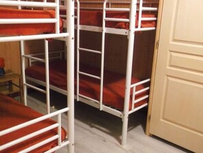 Ein Schlafzimmer mit Etagenbetten, weißen Metallgeländern und roter Bettwäsche.