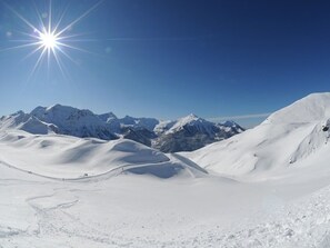 Eine verschneite Berglandschaft mit blauem Himmel und strahlender Sonne.