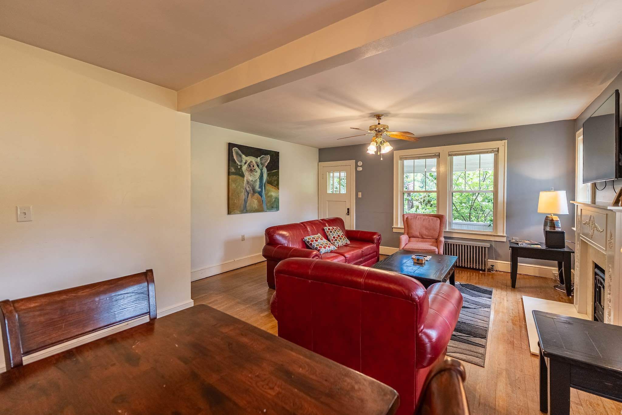 A living room with a red leather sofa, a wooden dining table, and a fireplace.