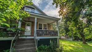 Ein zweigeschossiges Haus mit Veranda, Treppe und gepflegtem Rasen.