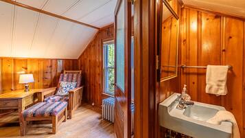 A wooden interior with a bench, a table, a radiator, and a sink with a towel.
