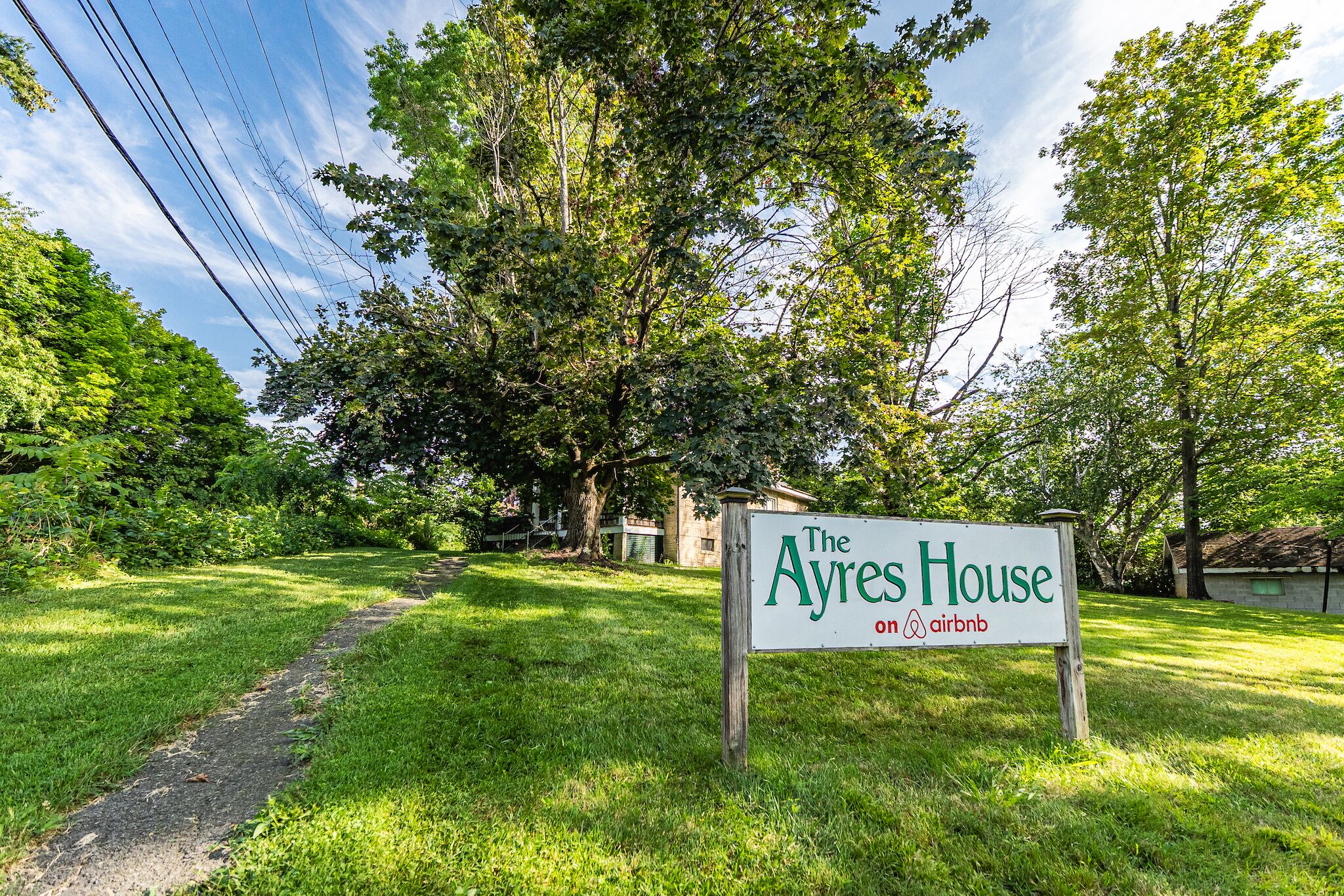 Une annonce pour « The Ayres House » sur Airbnb, entourée d’une végétation luxuriante et d’arbres.