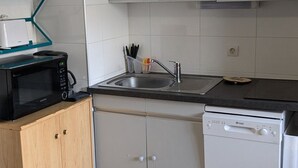 Una cocina compacta equipada con microondas, lavavajillas, pileta y alacenas.