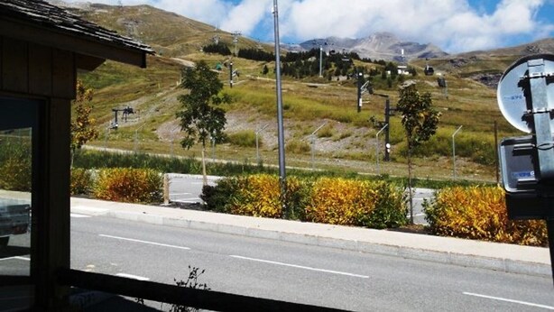 Vista desde una ventana sobre un camino con una montaña al fondo.