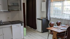 Una cocina compacta equipada con lavavajillas, un refrigerador pequeño y un comedor con mesa y sillas.