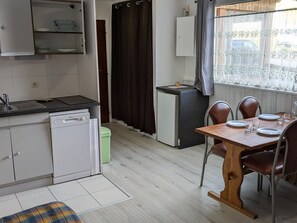 A compact kitchen with a dishwasher, a small refrigerator, and a dining area with a table and chairs. - Cozy studio at the foot of the slopes - 4 guests (Orcières Merlette)
