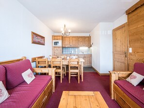 A cozy room with a wooden dining table, two wooden sofas, a wooden coffee table, and a kitchen area with wooden cabinets and a microwave. - Spacious apartment - 6 guests (La Toussuire)