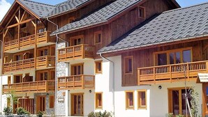 Ein mehrstöckiges Holzgebäude mit Balkonen, einer Steinfassade und einem geneigten Dach.