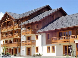 A multi-story wooden building with balconies and a stone facade. - Spacious apartment - 6 guests (La Toussuire)