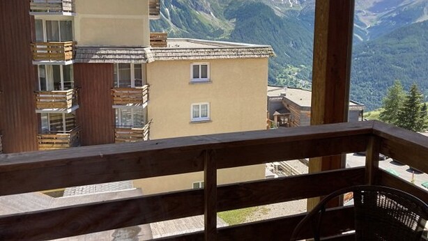 Ein Balkon mit Holzgeländer mit Blick auf eine gebirgige Landschaft.