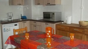 A compact kitchen with wooden cabinets, a microwave, a coffee maker, and a table with a red and grey tablecloth. - Bright apartment near slopes - 8 guests (Orcières Merlette)