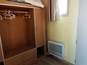 A room with a wooden wardrobe, a radiator, and a window with curtains.