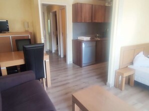 A room with a bed, a small desk, a chair, a sofa, and a kitchenette. - Cozy apartment, slopes view - 4 guests (Isola 2000)