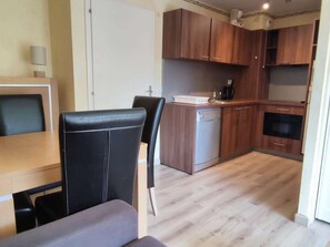 A compact kitchen with wooden cabinets, a built-in oven, and a dishwasher.
