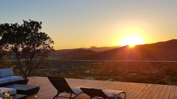 A wooden deck with two lounge chairs, a sofa, and a view of the sunset over a valley. - Villa with sea view, pets welcome - 12 guests (Bormes-les-Mimosas)