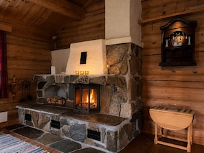 A stone fireplace with a fire, a wooden bench, and a wall-mounted shelf with decorative items.