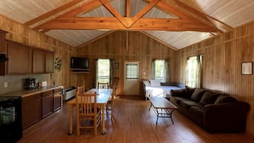 Una cabaña amplia con interior de madera, comedor, sofá y televisor.