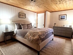 Une chambre à coucher avec un lit, des tables de chevet, une commode et une porte.
