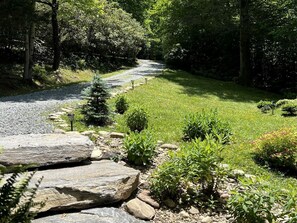 A gravel path leading through a garden with large rocks and various shrubs.