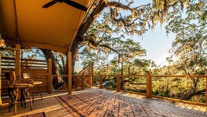 An outdoor deck with a patterned mat, wooden chairs, and a canopy. - Unique Marshfront Treehouse Stay with Heated Soaking Tub & Adventure-Inspired Escape in Townsend, Georgia (Townsend)