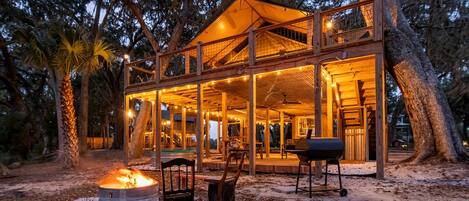 A wooden cabin with a covered deck, outdoor seating, and a fire pit.