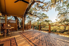 An outdoor deck with a patterned mat, wooden chairs, and a canopy.