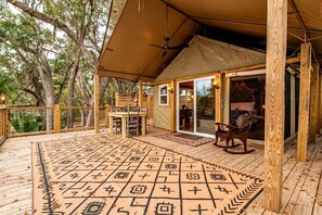 A covered outdoor area with a wooden deck, a patterned rug, and a horse statue.