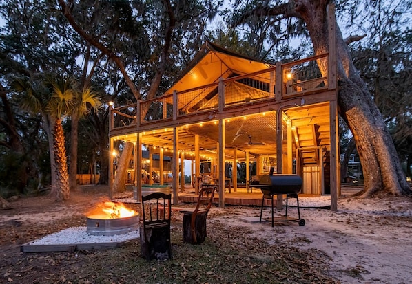 A wooden cabin with a covered deck, outdoor seating, and a fire pit.