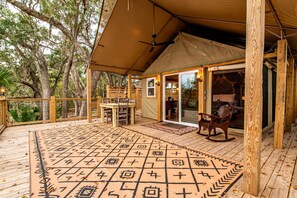 A covered outdoor area with a wooden deck, a patterned rug, and a horse statue.