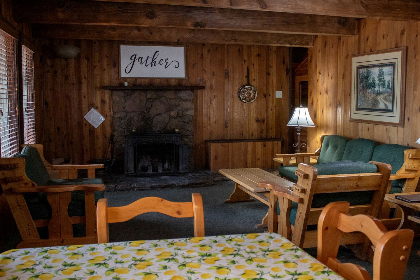 Ein gemütliches Lodge-Zimmer mit Kamin, Holzmöbeln und einem Schild mit der Aufschrift 'gather'.