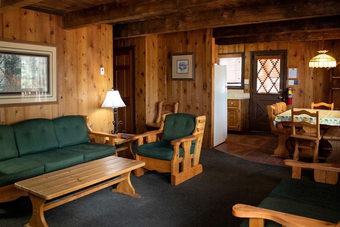 A wooden interior with a sofa, chairs, a table, and a dining area.