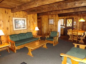 A wooden interior with a sofa, chairs, a table, and a dining set. - Spacious Cabin with Large Porch Ideal for Groups in Arizona (Flagstaff)