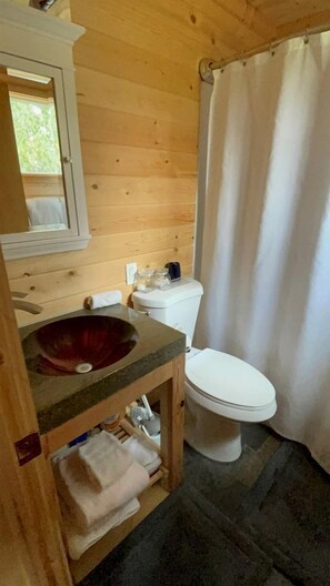 A wooden cabin bathroom with a stone sink, white toilet, and a shower curtain. - Relaxing Log Cabin Nestled in the Trees near Yellowstone, Idaho (Island Park)