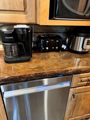 A kitchen with a Keurig coffee maker, toaster, and a stainless steel dishwasher. - Relaxing Log Cabin Nestled in the Trees near Yellowstone, Idaho (Island Park)