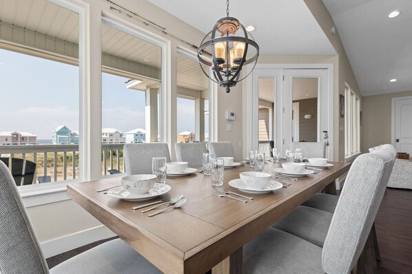 A dining area with a long table set for six, large windows, and a view of the beach. - New Listing!  In Morgantown w/ Pools, Tennis/Pickleball (Gulf Shores)