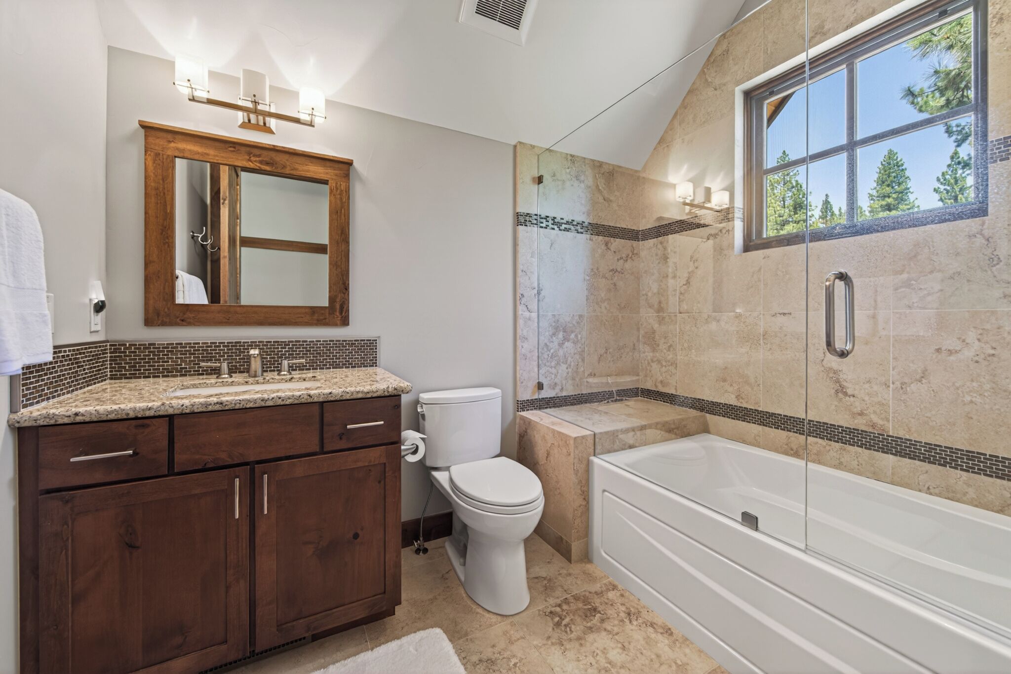 A bathroom with a wooden vanity, a toilet, a bathtub, and a shower with a glass door.