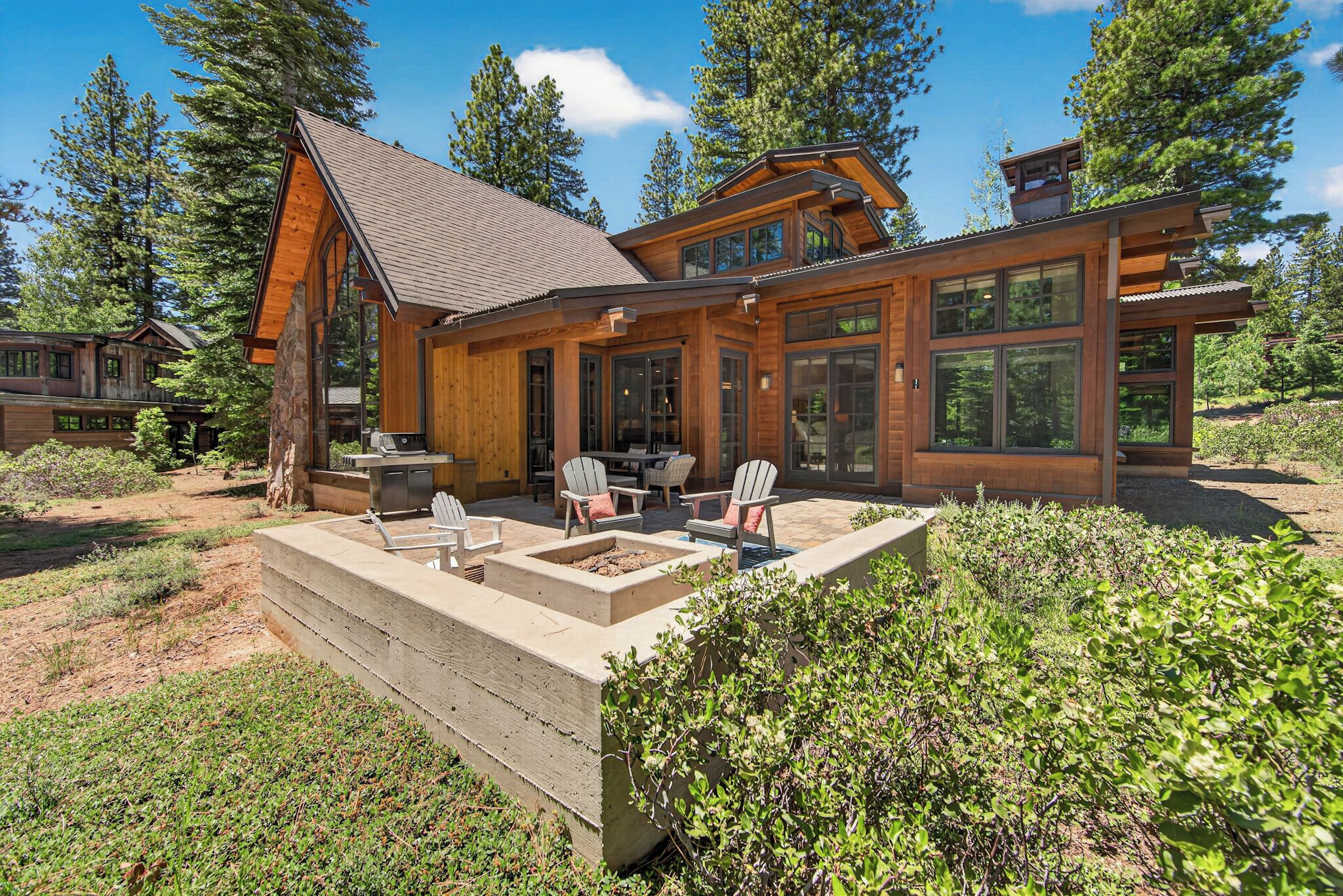 A modern log cabin with a patio, outdoor seating, and a fire pit.