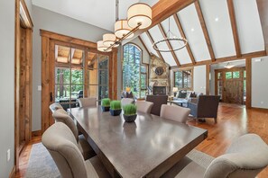 A spacious dining area with a long table, multiple chairs, and potted plants. - Monthly Lease - Signature Lodge at Martis Camp by Tahoe Getaways - 4BR Estate! (Truckee)