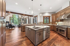 A spacious kitchen with wooden cabinets, a central island, stainless steel appliances, and large windows. - Monthly Lease - Signature Lodge at Martis Camp by Tahoe Getaways - 4BR Estate! (Truckee)