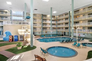 Ein mehrgeschossiges Hallenbad mit mehreren Schwimmbecken, Liegestühlen und Getränkeautomaten.
